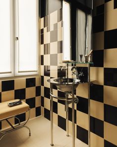 a bathroom with black and white checkered tiles on the walls, sink and mirror