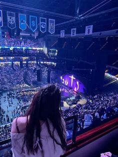 a woman standing in front of a crowd at a sporting event looking out into the stands