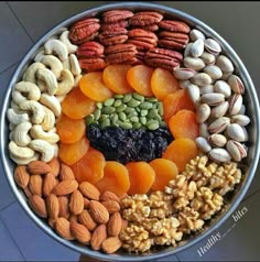 an assortment of nuts and dried fruits in a metal bowl