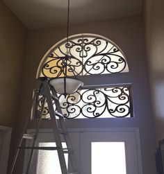 a light that is on top of a metal stepladder in front of a window