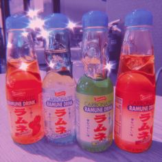 three bottles of various flavored drinks sitting on a table with the sun shining through them