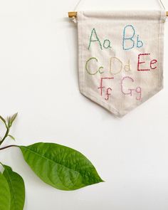 a white wall hanging on the side of a wall next to a potted plant