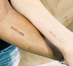 two people with matching tattoos on their arms, one is holding the other's arm