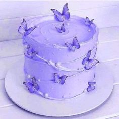 there is a three layer cake with purple butterflies on the frosting and icing