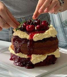 a person placing cherries on top of a cake