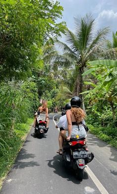 two people riding motorcycles down a road with palm trees in the backgrouds