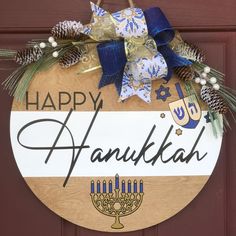 a happy hanukkah sign hanging on a door with pine cones and evergreens