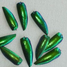 six shiny green objects sitting on top of a table