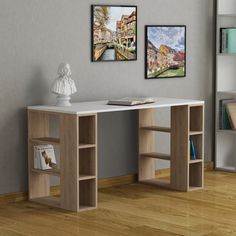 there is a white desk with two pictures on the wall and a book shelf in front of it