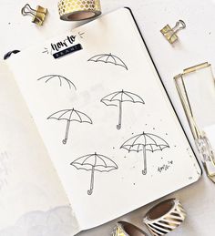 an open planner with umbrellas drawn on it next to some shoes and other items