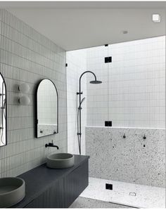 a bathroom with two sinks, mirrors and a shower head mounted to the side of the wall