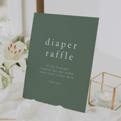 a card that says diaper raffle on it next to a candle and flowers