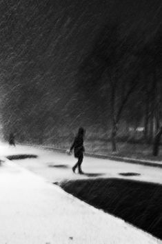 a person walking down a sidewalk in the snow with an umbrella over their head as it is snowing