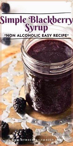 a jar filled with blackberry syrup on top of a wooden table next to blackberries