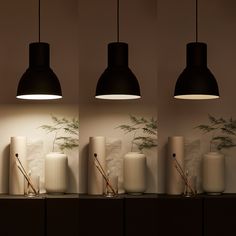 three lamps hanging from the side of a wall next to vases with plants in them