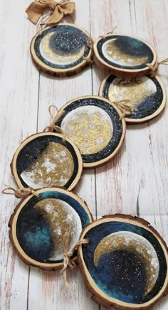 four pieces of wood that have been decorated with gold and blue paint on them, sitting on a white wooden surface