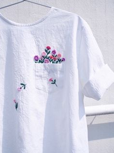 a white t - shirt with pink flowers in the pocket