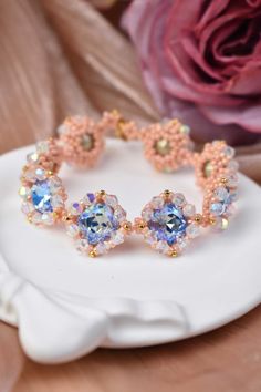 a close up of a bracelet on a white plate with flowers in the back ground