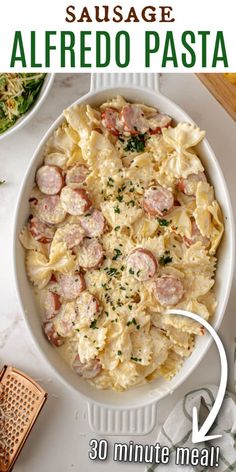 the recipe for sausage alfredo pasta is in a white bowl on top of a table