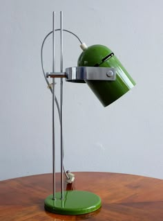 a green table lamp sitting on top of a wooden table