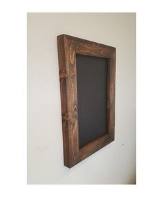 a chalkboard mounted to the wall in a wooden frame with an opening at the bottom