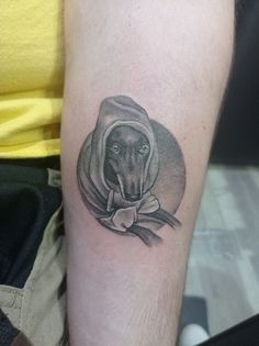 a man's arm with a black and white tattoo of a dog wearing a hoodie