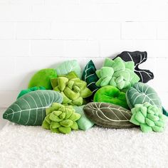 a pile of green plants sitting on top of a white rug next to a brick wall