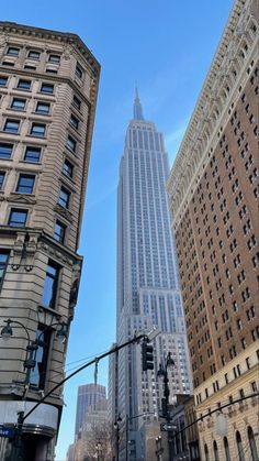 the empire building towering over other tall buildings in new york city, ny on a sunny day