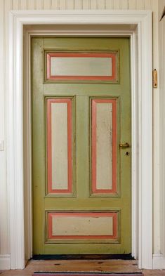 the front door is painted green and has pink trim on it, along with a rug