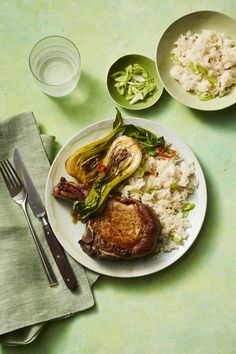 a plate with meat, rice and vegetables on it next to two glasses of water