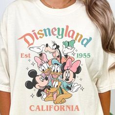 a woman wearing a white disneyland shirt with mickey mouse and friends on it's chest