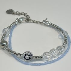 a bracelet with beads and a smiley face beaded on the front, in light blue