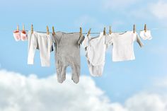 three baby ones hanging on clothesline with clouds in the background and blue sky above