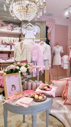 a room filled with lots of baby clothes and items on display in front of a chandelier