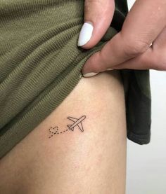 a woman with a small airplane tattoo on her thigh