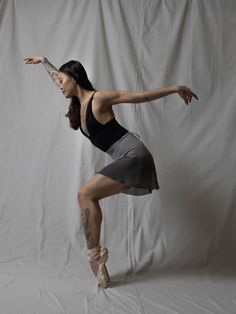 a woman is posing in front of a white backdrop with her arms outstretched and legs crossed