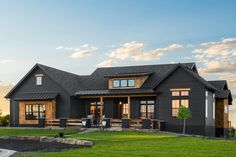 a black house with lots of windows on the front and side of it, surrounded by grass