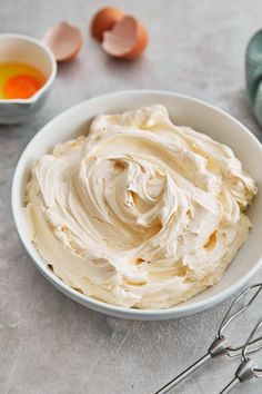 a bowl filled with whipped cream next to eggs