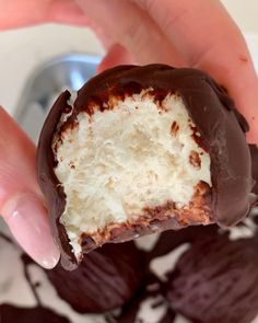 someone holding a half eaten chocolate covered doughnut