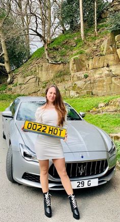 a woman posing in front of a car