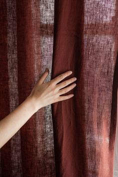 a person's hand reaching out from behind a curtain to touch the sheer fabric