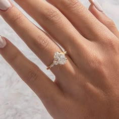 a woman's hand with a diamond ring on her finger and manicured nails