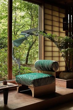 a green chair sitting on top of a wooden floor next to a tree filled forest