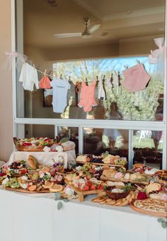 an assortment of food is on display in front of a window with clothes hanging from it