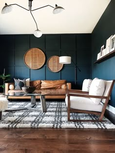 a living room filled with furniture and two lamps hanging from the ceiling over a rug