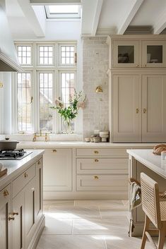 a kitchen filled with lots of counter top space and white cabinets under a skylight