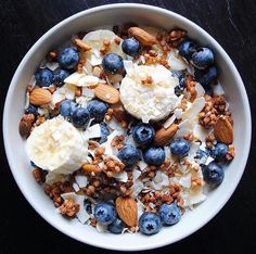 a bowl filled with granola and blueberries on top of a black tablecloth