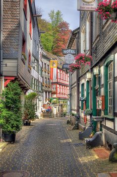 a cobblestone street in an old european town with colorful buildings and flowers on the windows