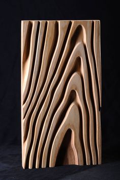 a wooden block with wavy lines carved into the wood, on a black background that appears to be made out of plywood