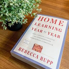 a book sitting on top of a wooden table next to a potted plant